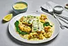 Tallerken med hvit fisk, blomkål, grønnkål og lys saus på et dekket bord