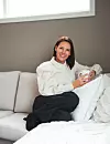 Kvinne (Caroline Leithe) sitter i lys sofa med hvit kopp i en moderne stue.