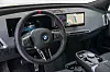 BMW-førerplass med digitalt instrumentpanel og stor midtskjerm. Førermiljøet i BMW iX er annerledes og spesielt med fine materialer og god brukervennlighet, bortsett fra koppholderne som sitter under armlenet.