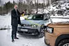 Mann kobler gul ladekabel mellom to Renault-biler på snødekt landevei. Fiat Grande Panda har en praktisk ladkabel i fronten som mater den 7 kW store ombordladeren.