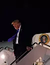 Donald Trump går ned trappen fra Air Force One om natten ved et flyplassområde.