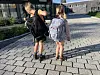 To barn med ryggsekker går på steinlagt vei foran en skolebygning
