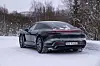 Svart Porsche Taycan sett bakfra på snødekt vei i vinterlig skog. Taycan som sportssedan er mer tro mot Porsches filosofi enn de mer populære Cross turismo-versjonene.