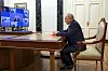 Vladimir Putin sitter ved et skrivebord i Kreml og leder et møte via videokonferanse på flere skjermer.