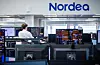 Meglerrom hos Nordea med skjermer fulle av markedsdata og en ansatt ved pulten.
