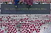 To NHS-ansatte sitter på National Covid Memorial Wall dekket av røde hjerter i London.