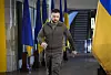 Volodymyr Zelenskyj går gjennom en korridor flankert av ukrainske flagg.