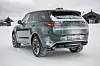 Grønn Range Rover Sport parkert på snødekt vei foran hytter om vinteren. Lakkfargen Giola Green sier mer enn 1.000 ord.