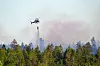 Helikopter slipper vann over røykfylt skog under skogbrann i Hobøl.