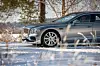 Grå Bentley sedan parkert på snødekt landevei mellom trær om vinteren.