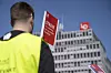 Streikevakt med gul vest holder rød streikeplakat foran LO-bygget i Oslo.