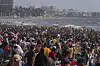 Stor folkemengde på Juhu-stranden ved bølgende sjø i Mumbai