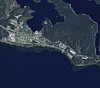 Satellittbilde av skogkledd område ved innsjø med veier og bygninger langs strandlinjen.