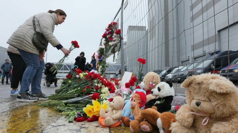 En kvinne kommer med blomster til gjerdet ved konserthallen i Moskva som ble utsatt for et terrorangrep fredag. Foto: Vitaly Smolnikov / AP / NTB