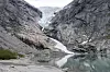 Briksdalsbreen som ender i en stille smeltevannssjø mellom bratte fjell i Olden.