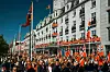 Folkemengde med norske flagg foran Grand Hotel i Oslo på en solrik dag