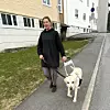 Person går på fortau med førerhund foran boligblokker