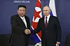 Putin og Kim håndhilser foran russisk og nordkoreansk flagg ved Vostochny kosmodrom.