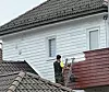Person maler husvegg fra stige ved enebolig