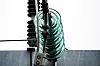 Detaljbilde av høyspentledning med grønne isolatorringer ved en transformatorstasjon.