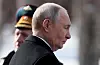 Vladimir Putin i profil utendørs med en offiser i bakgrunnen