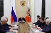 Vladimir Putin sitter midt ved et langt møtebord i Kreml omgitt av mannlige embetsmenn.