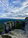 Bratte fjellformasjoner med skogkledde daler og dramatisk kveldshimmel. ratte fjellformasjoner med skog og en enslig turgåer på kanten i solnedgang. Johan Haugsrud (@explorewithjohan) på fjellhyllen Gygrestolen i Bø i Telemark, med utsikt mot Gygrestolen i Telemark, et av Johan Haugsruds anbefalte turmål for sommeren.