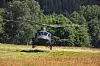 Militærhelikopter fra 339 SOAS i lav høyde over eng ved skog i Innlandet