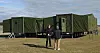 To personer foran grønt mobilt containeranlegg på gresslette