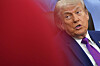 Donald Trump sitter i Det ovale kontor og snakker, delvis skjult av en rød uklar forgrunn.