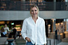 Person i hvit skjorte står i et moderne kontor- eller biblioteksbygg. Forbrukerøkonom Lene Drange i moderne kontormiljø illustrerer Norges Banks beslutning om å heve styringsrenten til 4,25 prosent.