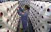 Arbeider sjekker rader av hvite fiberspoler i en fabrikkhall i Nantong.