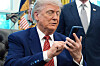 Donald Trump sitter ved skrivebordet i Det ovale kontor og betjener en smarttelefon.