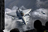 Eurofighter Typhoon-jagerfly flyr i formasjon over skydekket landskap.