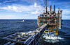 Offshore plattform i Nordsjøen med gangbru og kystvaktskip i bakgrunnen