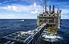 Offshore plattform i Nordsjøen med gangbru og kystvaktskip i bakgrunnen