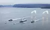 Marinefartøy i formasjon med lysende mottiltak over sjøen i en norsk fjord.