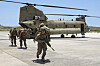 Amerikanske soldater forlater et militært CH-47-helikopter på en flystripe i dagslys.