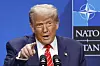 Donald Trump taler foran Nato-logoen og peker mot salen.