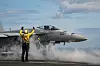 US Navy EA-18G Growler gjør seg klar til takeoff på hangarskip med mannskap på dekk.