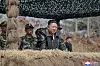 Kim Jong-un står i skytterstilling og observerer en militærøvelse sammen med offiserer.