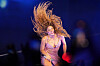 Shakira i glitrende kjole synger energisk på opplyst scene.