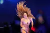 Shakira i glitrende kjole synger energisk på opplyst scene.