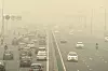 Biler og motorsykler kjører på motorvei innhyllet i tykk smog i New Delhi.