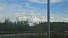 Kraftlinjer over vei ved skogkledd område under blå himmel