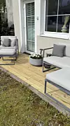 Liten treplatting med utemøbler og blomsterkrukke foran en leilighetsdør.
