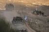 Militære kjøretøy med israelske soldater og flagg kjører på grusvei ved Golanhøyden.