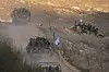 Militære kjøretøy med israelske soldater og flagg kjører på grusvei ved Golanhøyden.
