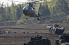 Militærhelikopter og pansrede kjøretøy under øvelse på jorde i Litauen.