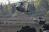 Militærhelikopter og pansrede kjøretøy under øvelse på jorde i Litauen.